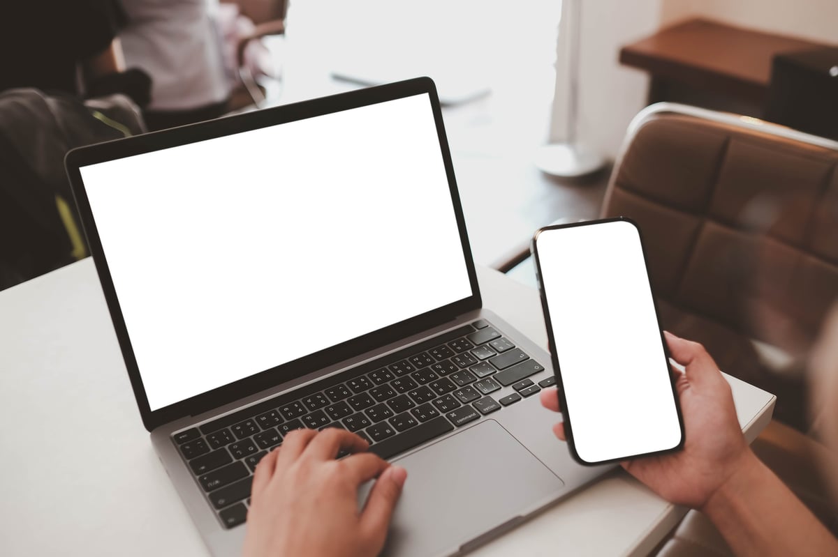 Woman at a cafe using laptop and phone with blank screens — modern local business website design by Cloudline AI